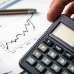 Close‑up of a hand holding a calculator beside a line chart with a fee percentage label over blurred financial documents.